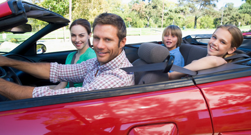 family riding in insured red sports car